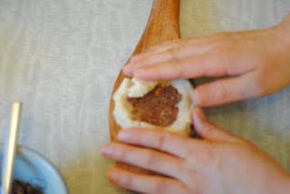 After stuffing the kahk dough, the ends are carefully folded over to seal it.